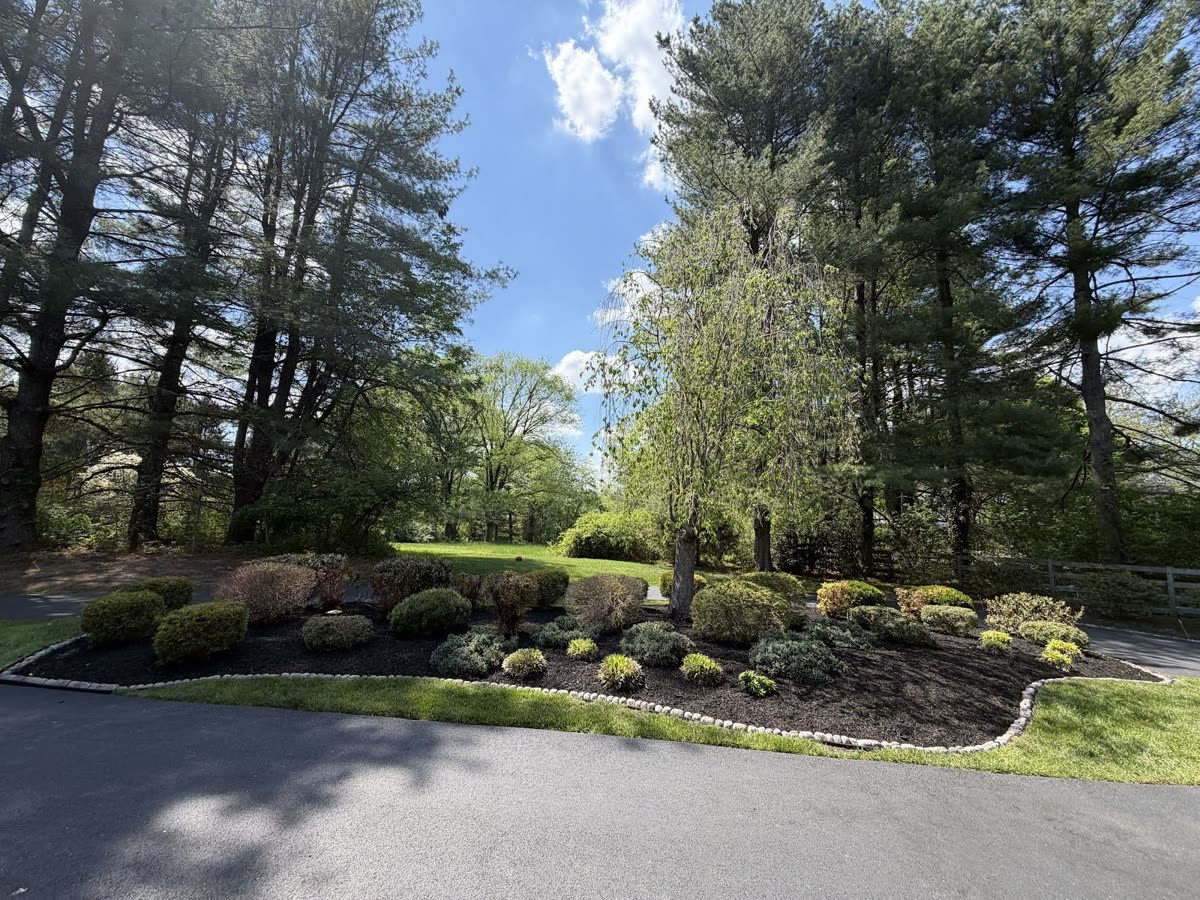 Designed corner island garden bed with fresh mulch and stone edging installed by Green Diamond in Reisterstown, MD